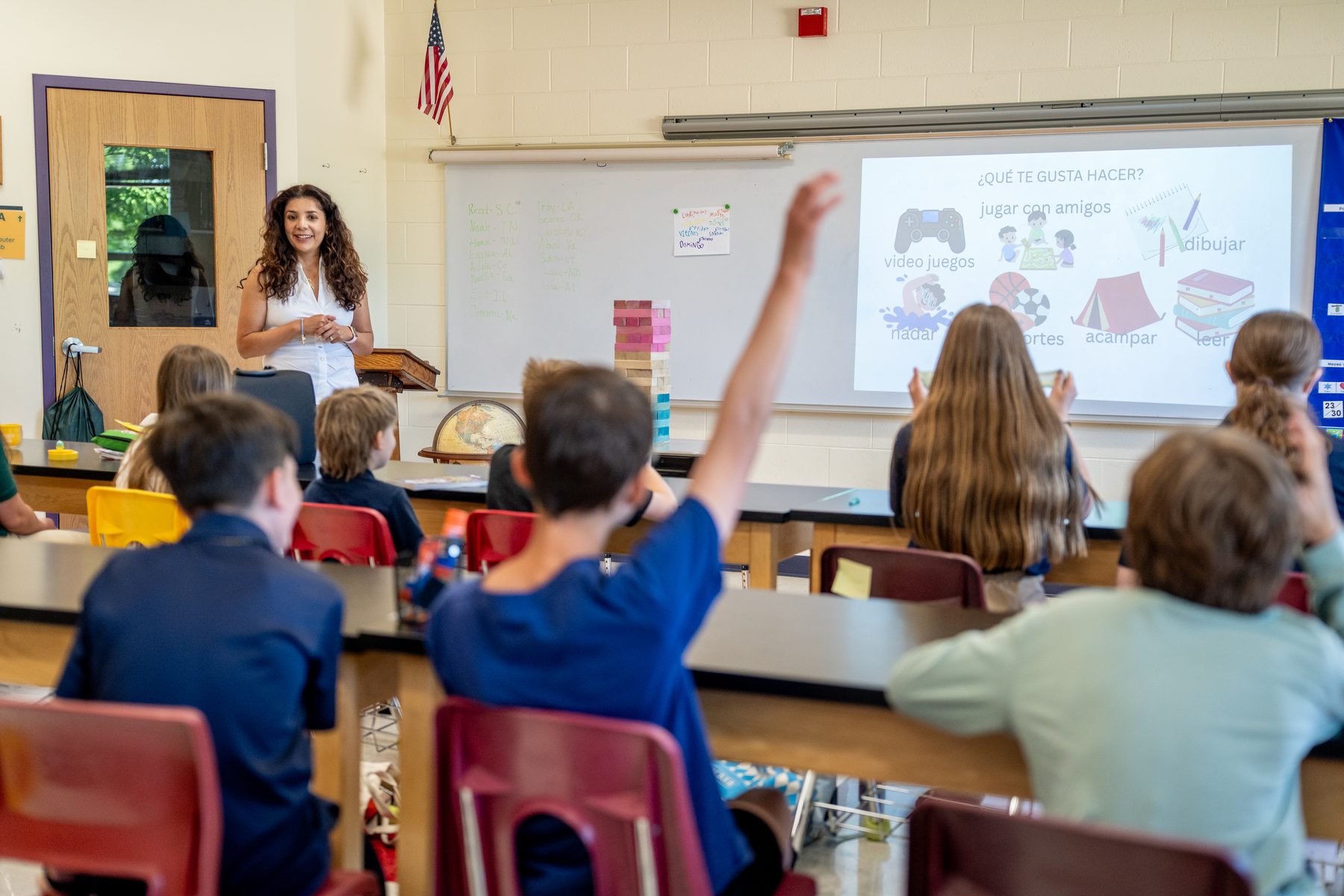 Students with raised hands during a Lake Country Spanish lesson